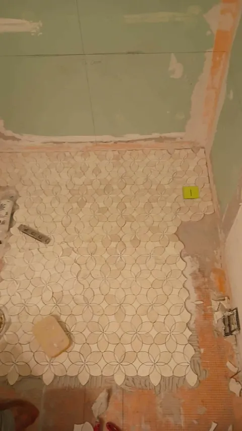 Marble floral-mosaic floor tile being set in the bathroom