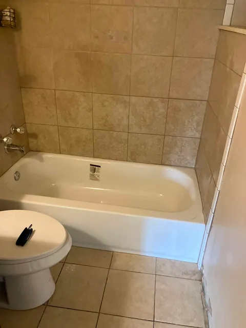 Bathroom before remodel — dated tan tile tub surround and old fixtures