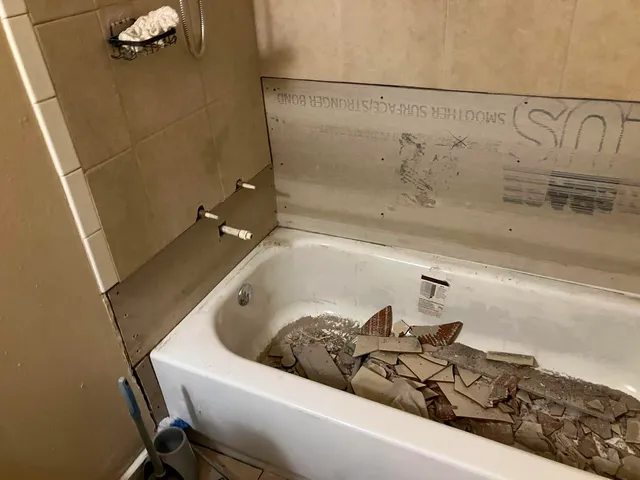 Bathroom demo — old tile stripped from the tub surround