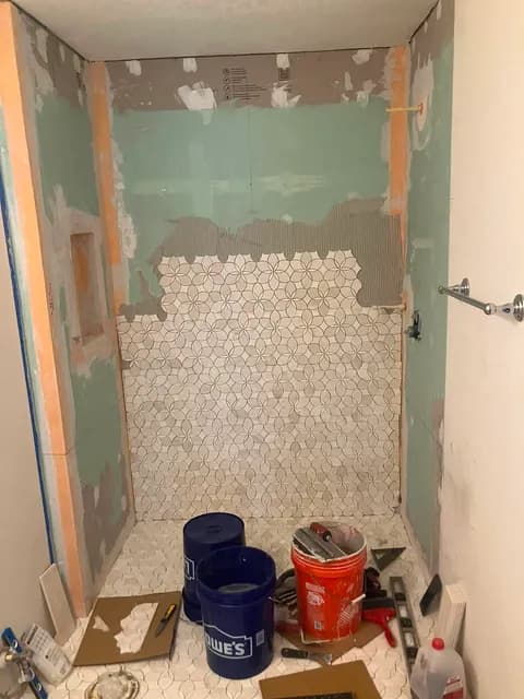 Shower remodel in progress — marble mosaic floor going in over cement board