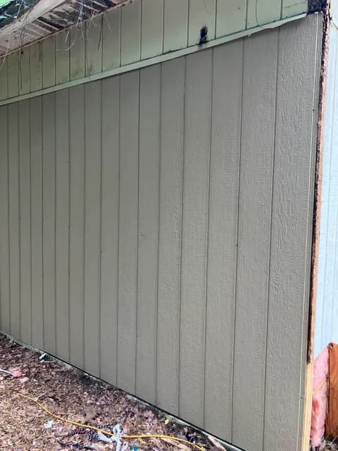 Garage after siding replacement — clean new panel ready for paint
