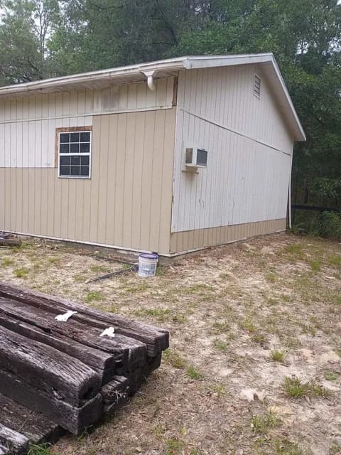 Detached garage before siding work — weathered cream exterior