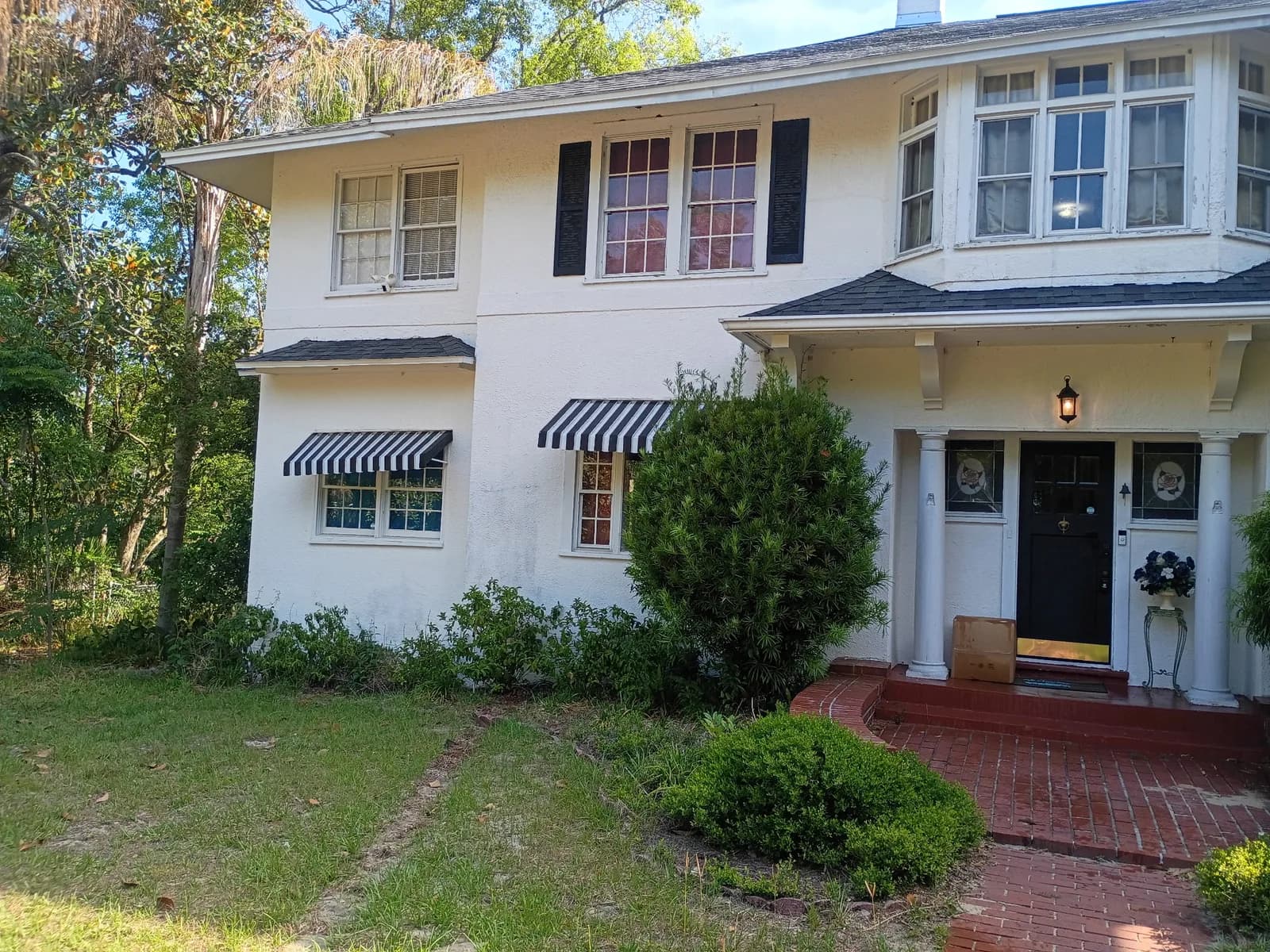 Two-story home front exterior before work — white stucco with black shutters