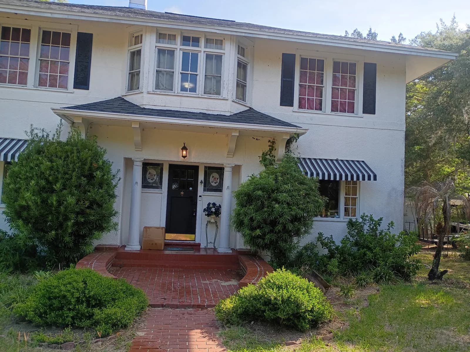 Two-story home front exterior before — brick entry steps and awnings