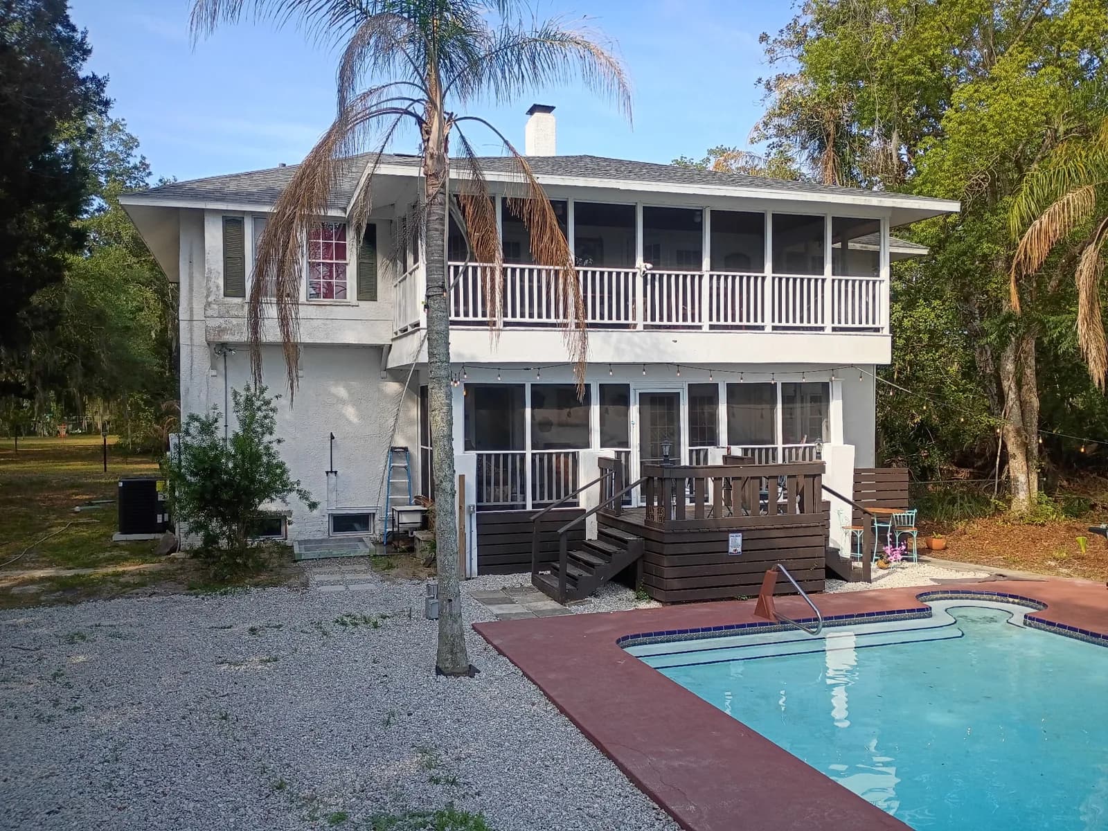 Two-story home backyard before — pool area and screened rear porch