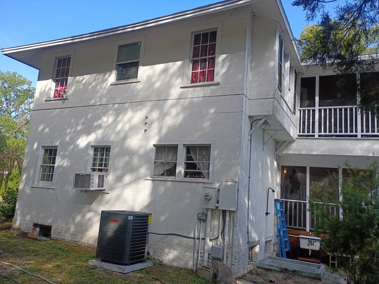 Two-story home rear exterior before — back porch and balcony visible