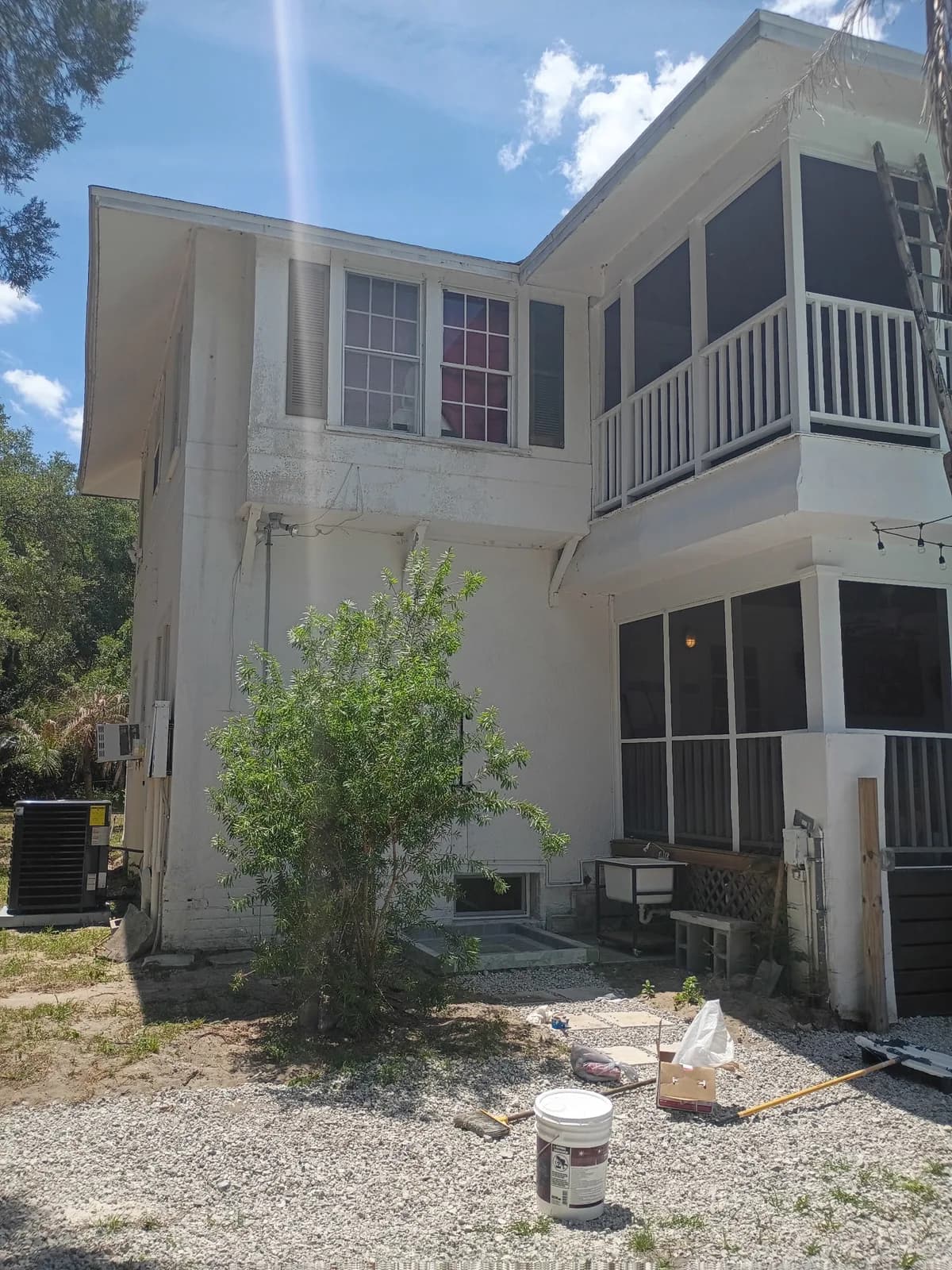 Two-story home rear during exterior work — paint supplies on site