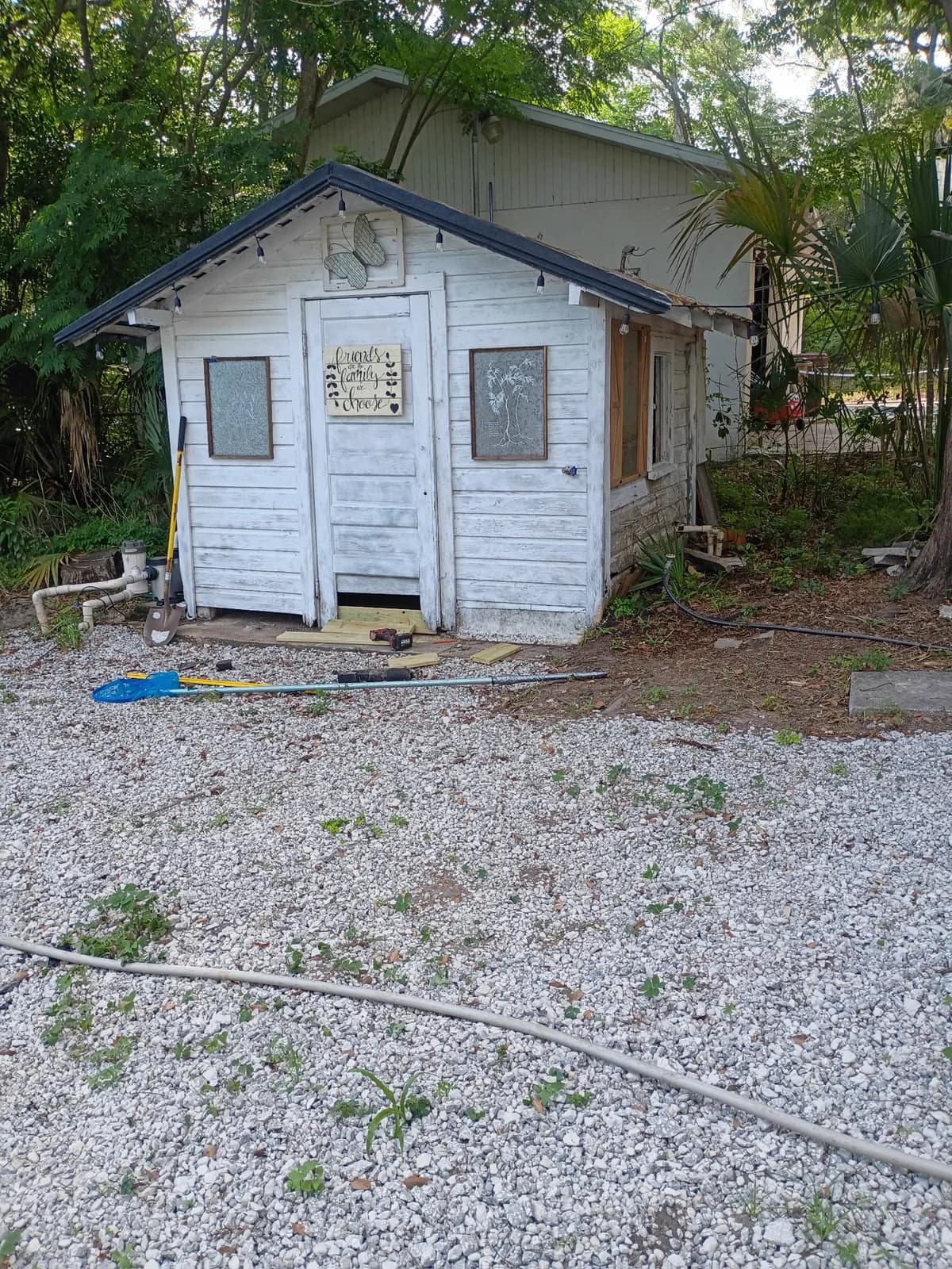 Outbuilding before painting — worn white siding and old door