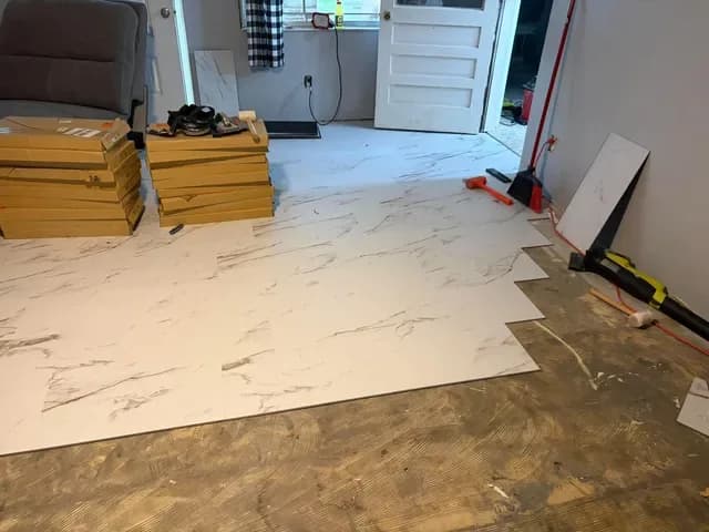 Large white marble-look floor tile being laid in a living room