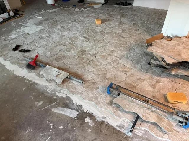 Cutting stone-look tile to fit as the new floor spreads across the room