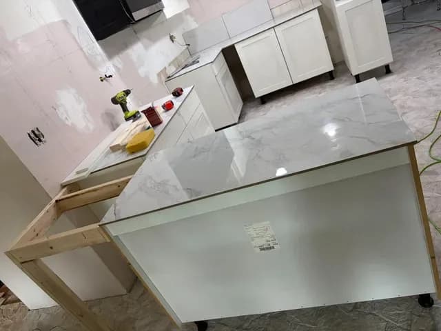 Kitchen island framed out with a white veined countertop set on top