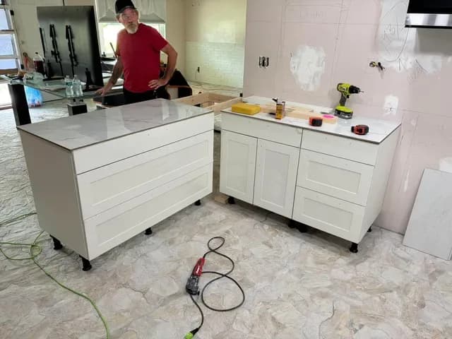 Kitchen island and corner cabinets with white veined countertops installed