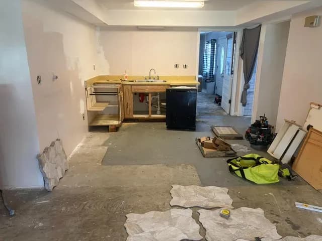 Kitchen before remodel, old cabinets torn out down to a bare concrete floor