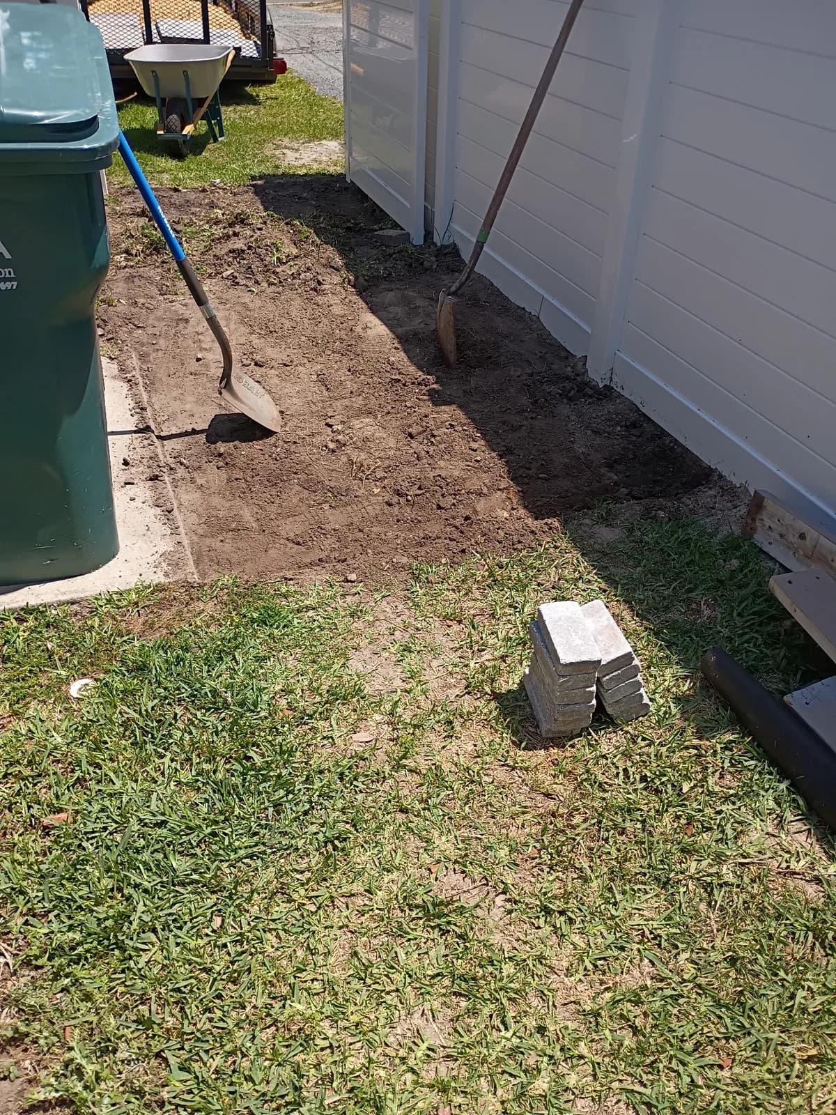 Side yard before — ground dug out, pavers staged and ready to set