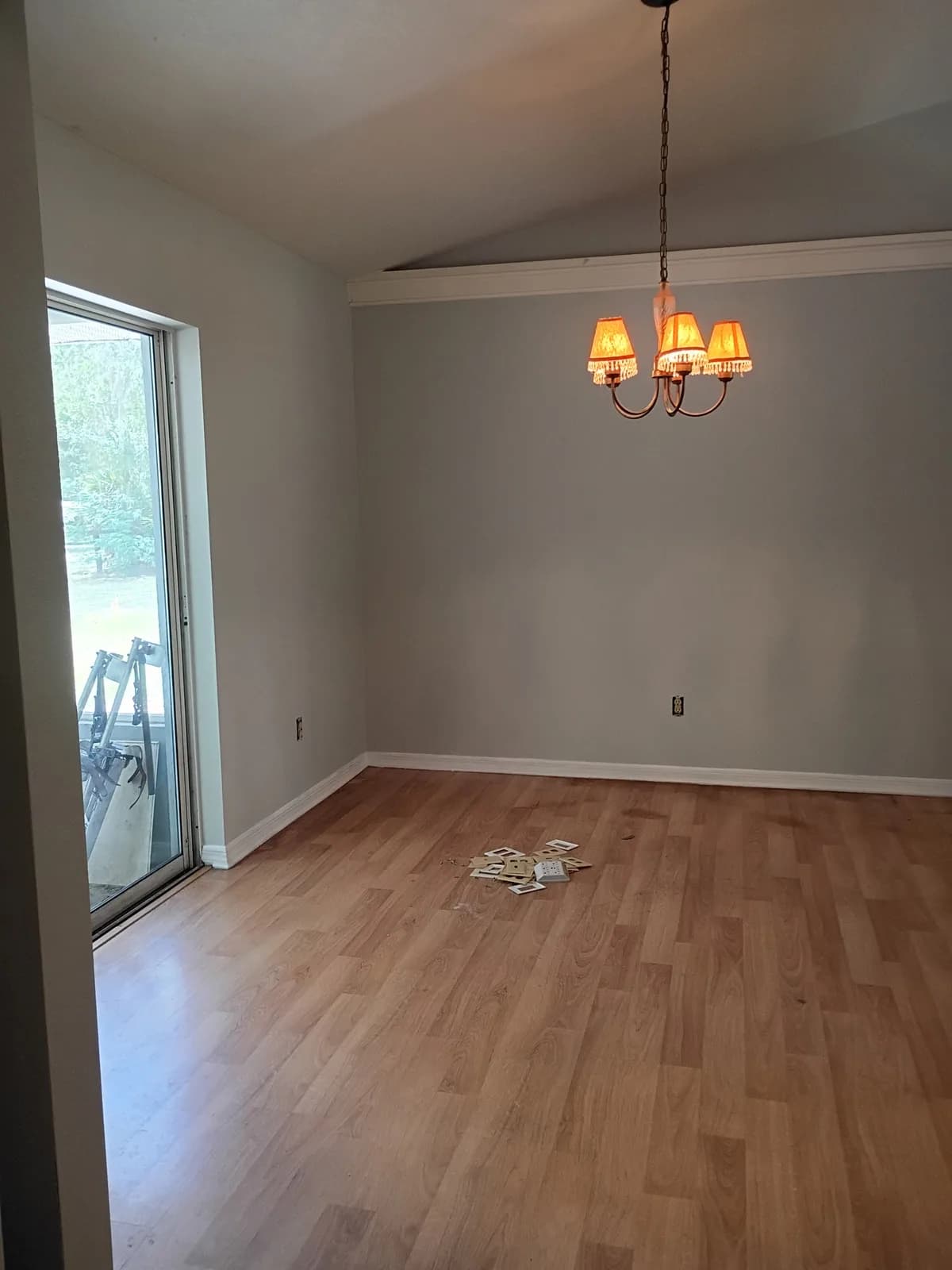 Dining room after painting — light gray walls with chandelier and slider