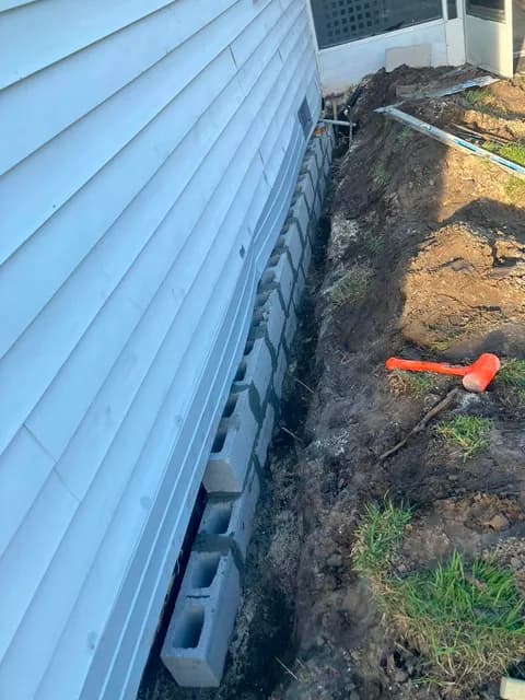 Concrete block footer course set along a dug-out foundation trench