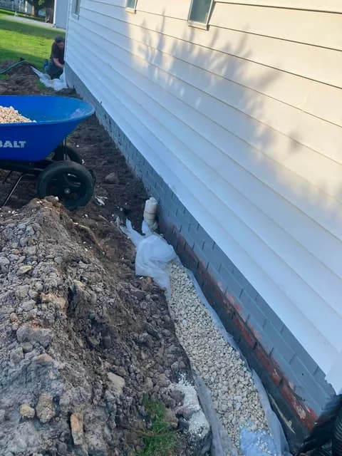 French drain installation — gravel-filled trench along the foundation
