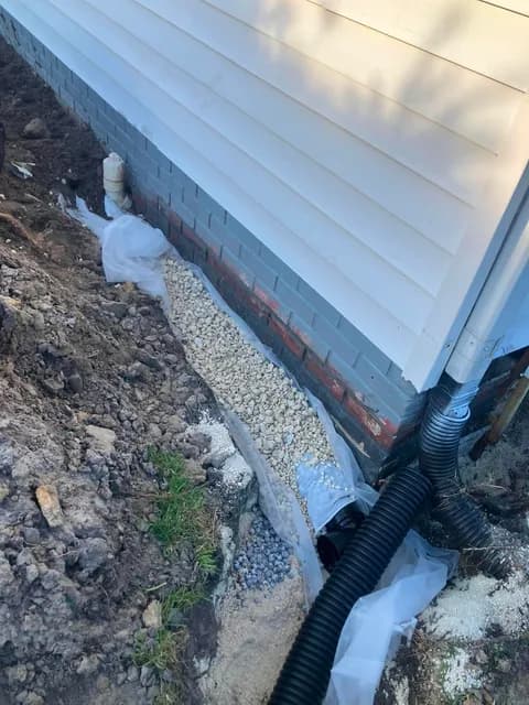 French drain with perforated pipe and gravel routing water from the foundation