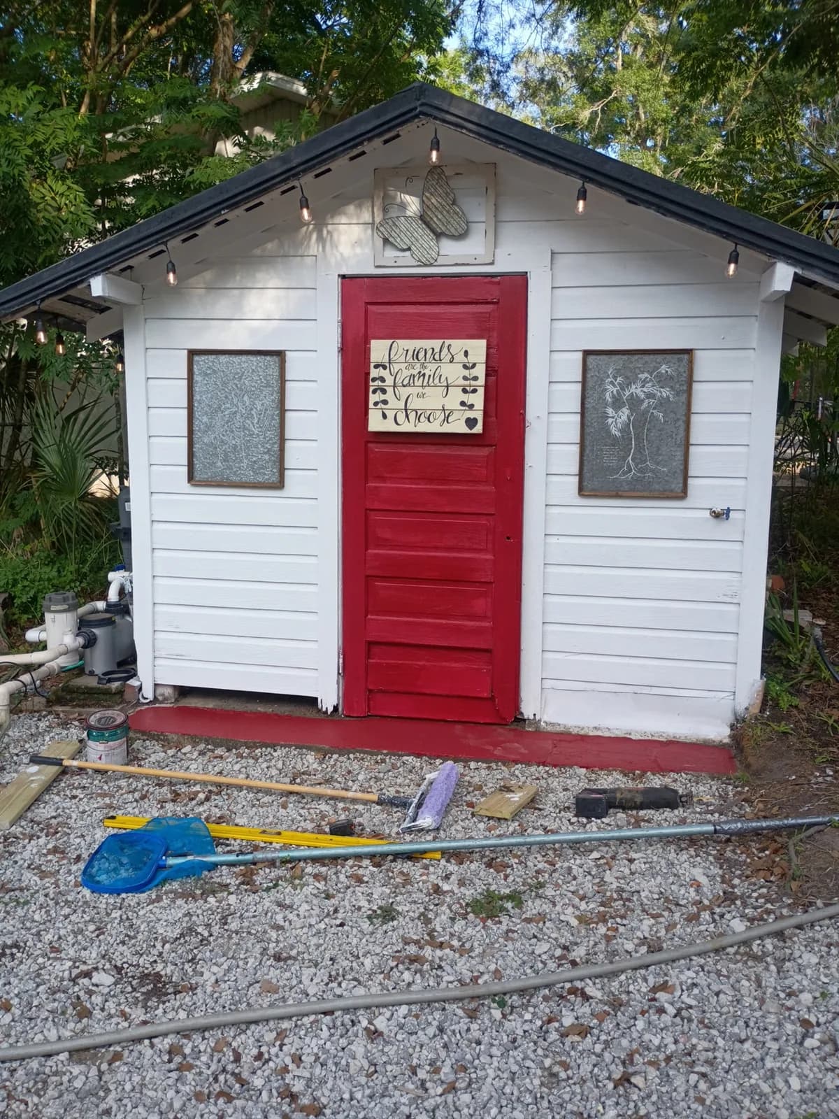 Freshly painted outbuilding with bright red door and string lights